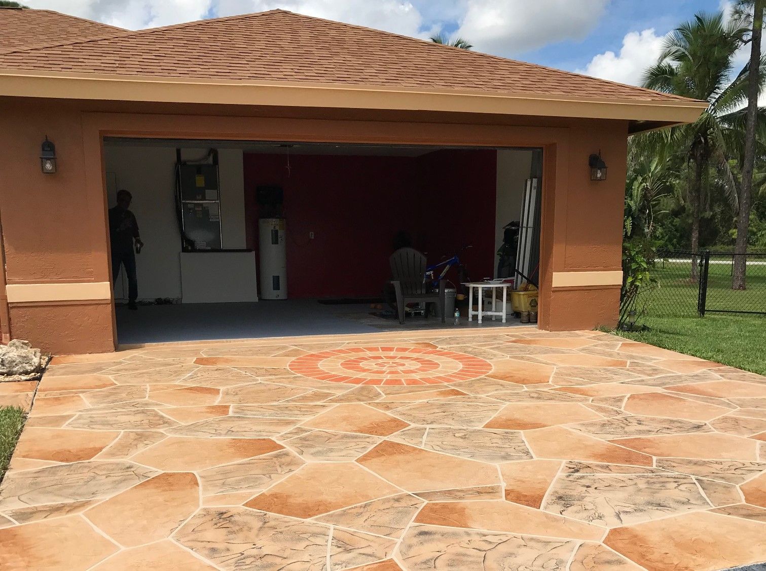 Stamped concrete driveway with a decorative medallion outside an open garage