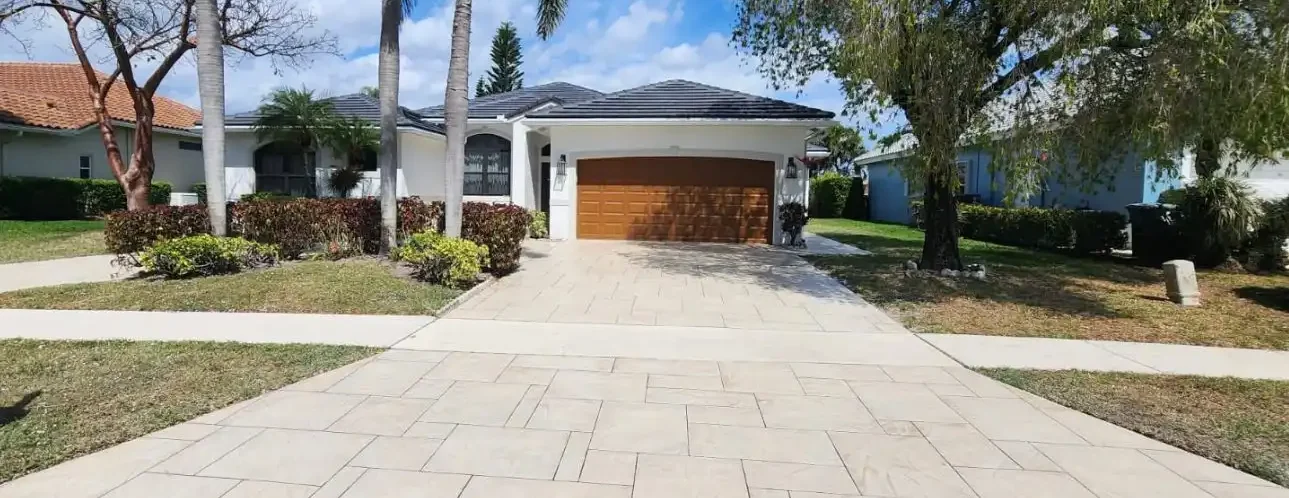 Stamped concrete driveway leading to a residential garage with a decorative tile finish