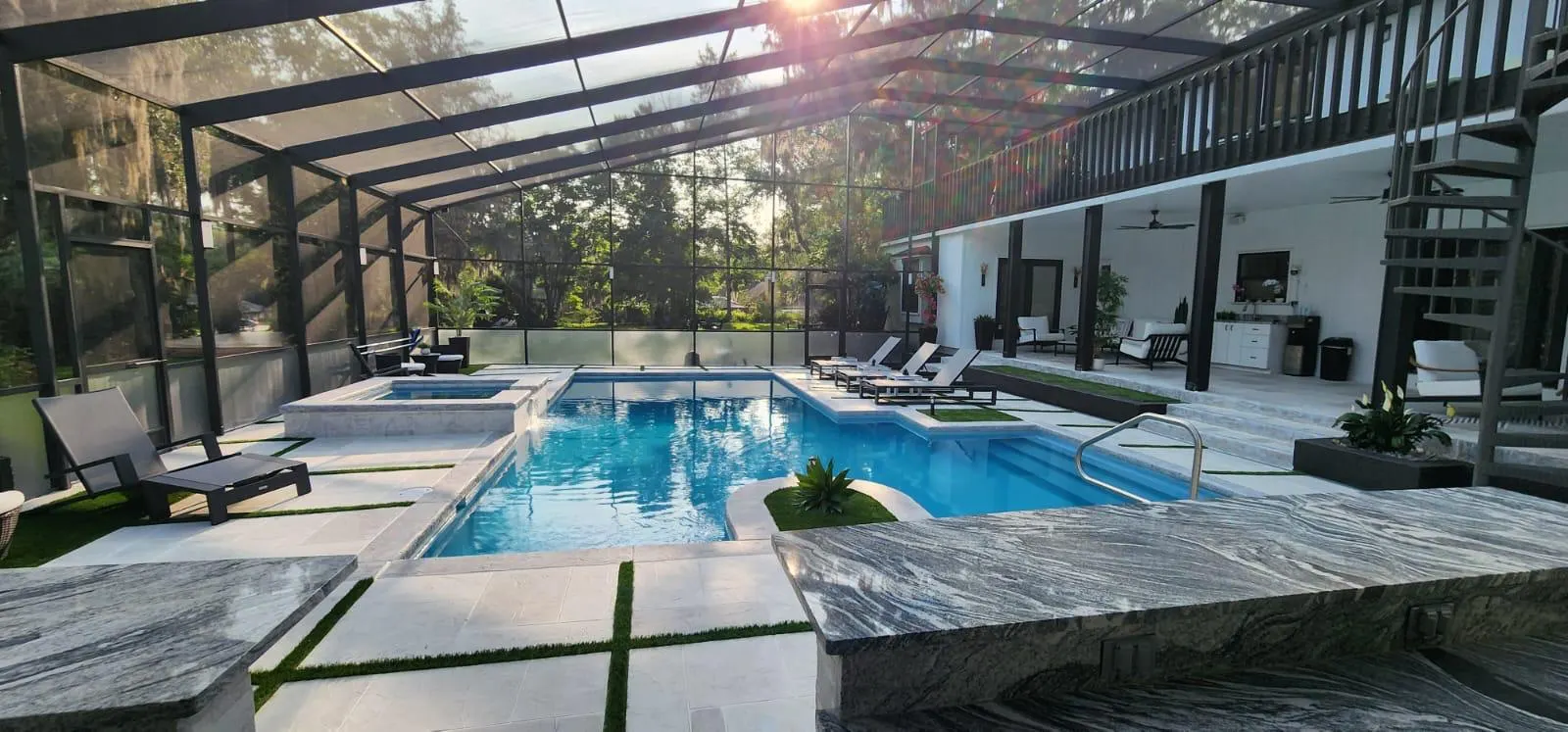 Screened pool enclosure with a finished stamped concrete pool deck surrounding the water